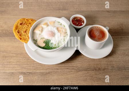 Un bol de bouillon de lait de changua colombien avec des œufs sur une table en bois Banque D'Images