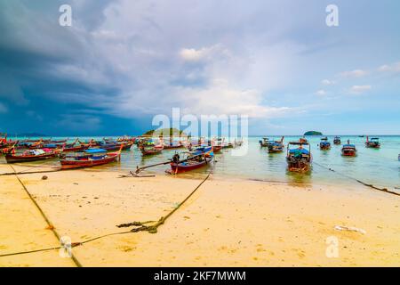 Petit port avec de longs bateaux à queue à l'île de Ko Lipe, en Thaïlande, peu avant la tempête tropicale. Grands et lourds nuages sombres au-dessus de la mer. Détail de Bo en bois Banque D'Images