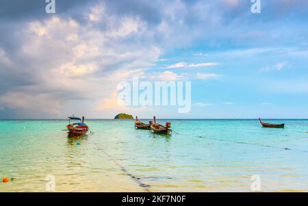 Petit port avec de longs bateaux à queue à l'île de Ko Lipe, en Thaïlande, peu avant la tempête tropicale. Grands et lourds nuages sombres au-dessus de la mer. Détail de Bo en bois Banque D'Images