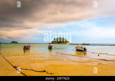 Petit port avec de longs bateaux à queue à l'île de Ko Lipe, en Thaïlande, peu avant la tempête tropicale. Grands et lourds nuages sombres au-dessus de la mer. Détail de Bo en bois Banque D'Images