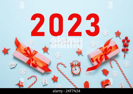 2023 boîtes cadeau ou cadeau avec arcs rouges, nombres et étoiles confetti vue de dessus. Arrière-plan de Noël et du nouvel an. Pose à plat. Banque D'Images