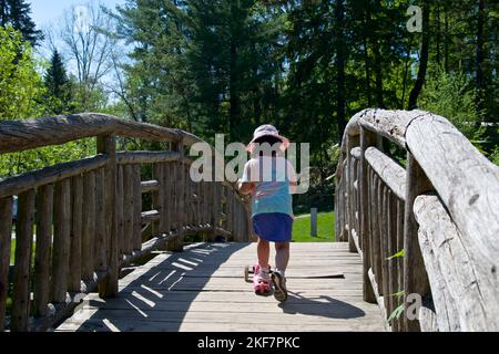 Une jeune fille qui traverse un pont dans un parc public au printemps Banque D'Images