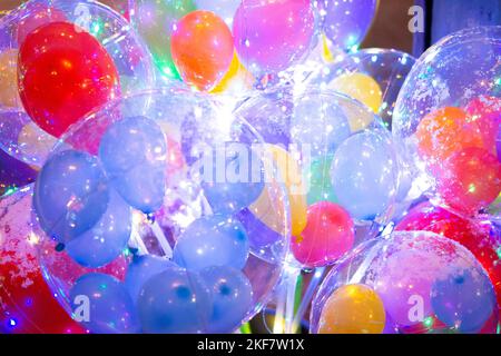 Ballons avec guirlande lumineuse à l'intérieur. Arrière-plan abstrait et coloré. Beaucoup de ballons colorés différents avec une guirlande clignotante à l'intérieur de gros plan. Concept vacances, festival, célébrer, nouvel an, Noël Banque D'Images