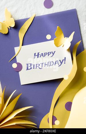 Texte « Joyeux anniversaire » sur carte papier. Noël printanier fête de Noël style papier art design. Fond de papier jaune violet superposé avec fleurs, cercles Banque D'Images