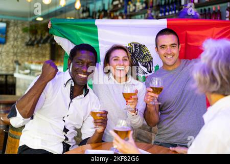 Joyeux fans de l'équipe mexicaine célébrant la victoire au bar de nuit Banque D'Images