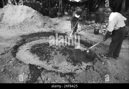 Comté d'Ilfov, Roumanie, 1990. Hommes mélangeant béton sec avec eau à l'extérieur d'une résidence privée dans un village. Banque D'Images