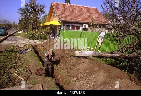 Snagov, comté d'Ilfov, Roumanie, env. 2000. Une tranchée creusée sur le bord de la route pour atteindre la conduite d'eau ou d'égout. Banque D'Images