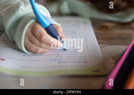 Étudier et l'éducation.Schoolgirl fait ses devoirs. L'enfant écrit avec un crayon dans un bloc-notes.gros plan crayon dans une main d'enfant. Banque D'Images