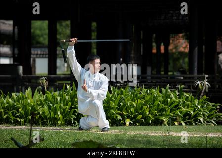 Jeune homme pratiquant le Tai Chi Sword traditionnel, Tai Ji dans le parc pour la santé, traditionnel chinois arts martiaux concept sur fond naturel . Banque D'Images