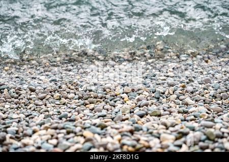 L'eau propre en cristal lave les cailloux qui se trouvent sur la plage de la mer. Les cailloux mouillés se trouvent près du bord de l'eau, attendant que les vagues se roulent de près Banque D'Images