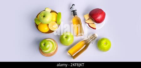 Composition avec bouteilles de vinaigre de cidre de pomme et fruits frais sur fond clair, vue du dessus Banque D'Images