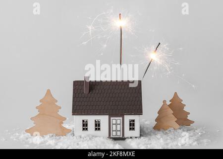 Composition avec des étincelles brûlantes, décoration de Noël, modèle de maison et neige sur fond blanc Banque D'Images