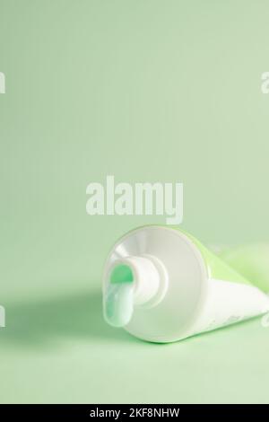 Un tube de dentifrice à la menthe goutte à goutte isolé sur fond vert - le concept de santé buccale Banque D'Images