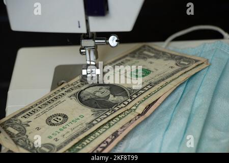 Les dollars américains se trouvent à côté des masques médicaux sur une machine à coudre, la production de masques médicaux, l'argent Banque D'Images