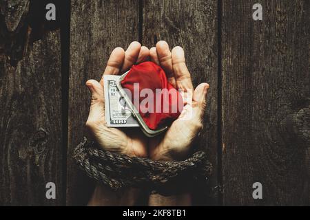 Portefeuille rouge avec dollars américains dans les mains liées de la fille sur la table Banque D'Images