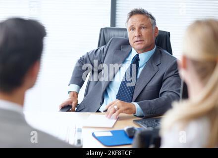 Tout le monde doit être au top de son jeu. Un responsable d'entreprise respecté qui tient une réunion avec deux jeunes collègues dans son bureau. Banque D'Images