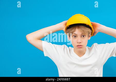 Portrait d'intérieur d'un beau artisan contrarié debout isolé sur fond bleu, regardant directement la caméra avec un casque jaune sur la tête. Personnes Banque D'Images