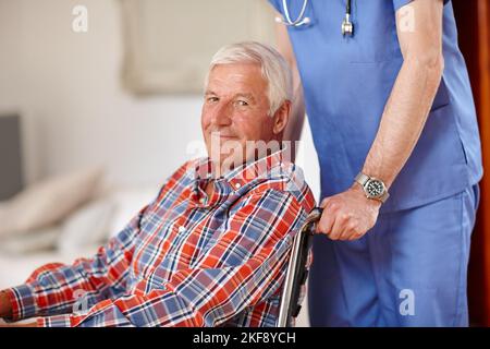 Je sais que j'ai les meilleurs soins médicaux. Un homme âgé est poussé dans un fauteuil roulant par une infirmière. Banque D'Images