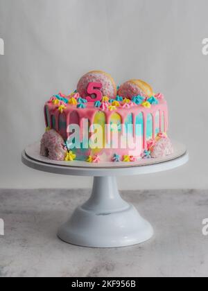 Gros plan d'un gâteau dépoli rose avec beignet et étoile royale brossée de plâstel parsemée d'une photo en studio blanche Banque D'Images