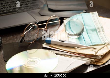 thermomètre disque carte globe et masque médical et ordinateur portable se trouvent sur le bureau du médecin dans le bureau, la médecine mondiale, bureau du médecin, le traitement en ligne et d Banque D'Images