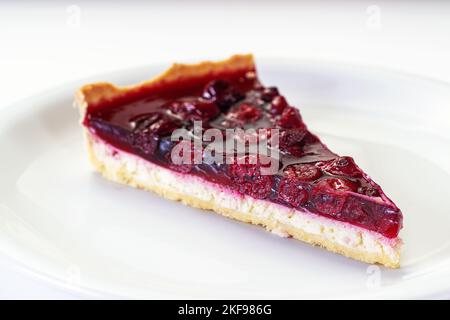 Morceau de cheesecake avec des cerises fraîches sur une assiette blanche Banque D'Images