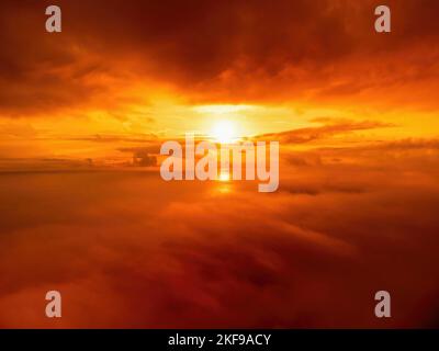 Un coucher de soleil rouge brûlant au-dessus de la mer et des nuages le drone vole au-dessus de nuages brumeux et moelleux. Résumé nature aérienne été océan coucher de soleil mer et ciel Banque D'Images