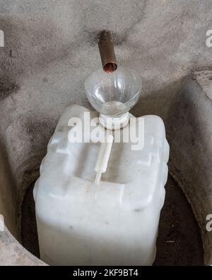 Des triches de mezcal distillées du tube de condensation dans une distillerie artisanale de mezcal dans la vallée d'Oaxaca, au Mexique. Cette petite famille b Banque D'Images