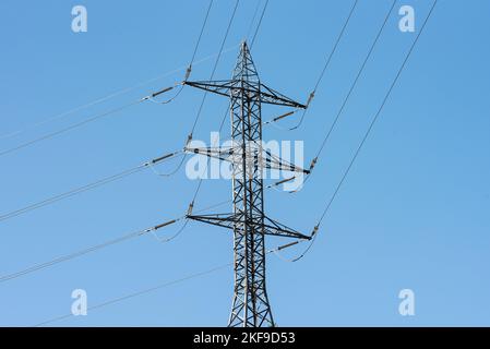 Les pôles électriques et les lignes haute tension se croisent avec le ciel bleu. Banque D'Images