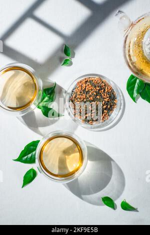 Thé vert de Genmaicha, ombre des portes de Torii, nappe blanche, théière en verre Banque D'Images