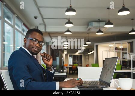 Un homme d'affaires afro-américain noir en costume d'affaires travaille à un ordinateur portable. Auto-développement et apprentissage à distance Banque D'Images