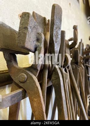 Diverses pinces pour forgeron pendre sur le mur dans un atelier de forgeron Banque D'Images