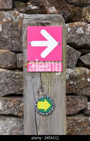 Forêt de Bowland, Clitheroe, Lancashire Royaume-Uni. Panneau de direction rose avec flèche blanche pointant vers Gisburn Forest Hub. Banque D'Images