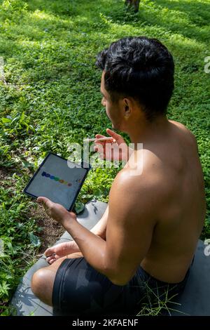 Un homme mène un cours de fitness virtuel avec un groupe de personnes à la maison lors d'une vidéoconférence Banque D'Images