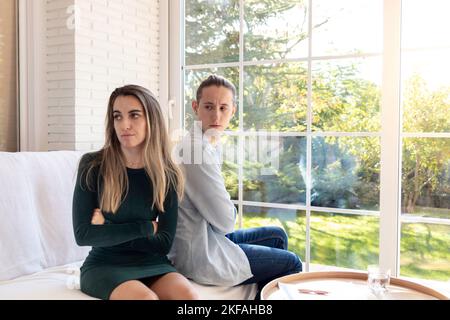 Les jeunes couples déçus se tournaient le dos les uns sur les autres tout en étant assis dans le canapé dans le salon avec jardin Banque D'Images