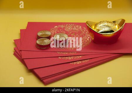 Paquets du nouvel an chinois avec lingots d'or et pièces sur fond jaune. Banque D'Images