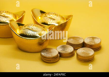 Lingots d'or chinois et pièces d'or sur fond jaune. Banque D'Images