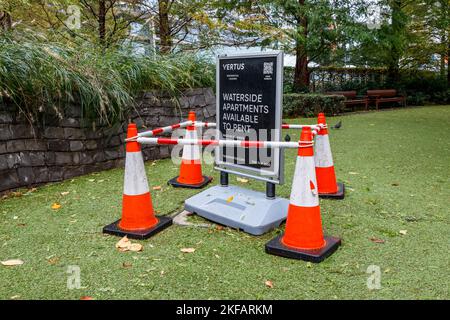 Une publicité pour la location d'appartements au bord de l'eau a été enorée par quatre cônes de signalisation à Jubilee Park, Tower Hamlets, Londres, Royaume-Uni Banque D'Images