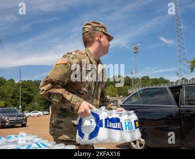 Un soldat avec un commandement de 66th troupes, la Garde nationale de l'armée du Mississippi, met de l'eau dans le siège arrière de la voiture d'une personne au stade Smith-Wills à Jackson, Mississippi, le 1 septembre 2022. Près de 600 gardes nationaux du Mississippi ont été établis sur sept sites de Jackson pour permettre aux résidents de recueillir de l'eau embouteillée et de l'eau non potable des camions d'eau pour aider à soulager certains effets de la crise de l'eau de Jackson. Banque D'Images