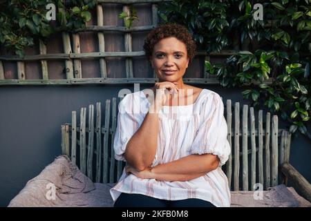 Portrait d'une femme d'âge moyen assise sur un banc et regardant l'appareil photo Banque D'Images