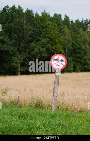 Un cliché vertical d'un panneau circulaire en trois parties interdisant les voitures, les vélos et les motos à la campagne Banque D'Images