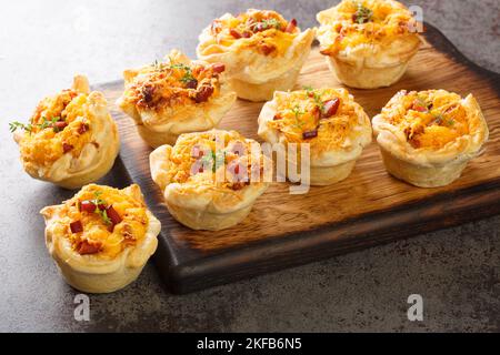 Des coupes de pain frais salées avec du jambon, des œufs et du fromage cheddar sur une planche en bois sur la table. Horizontale Banque D'Images