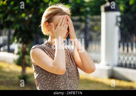 Portrait d'une femme de 40 ans réfléchie debout à l'extérieur parmi les arbres verts en croissance dans une allée et touchant le menton. Photo d'une femme d'âge moyen le jour ensoleillé Banque D'Images