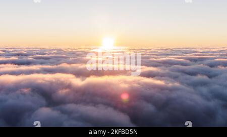Coucher de soleil sur des vagues de brouillard épais. Nuages sombres de brouillard. Le soleil brille sur de lourds nuages violets à haute altitude : coucher de soleil le soir au-dessus des nuages. Banque D'Images