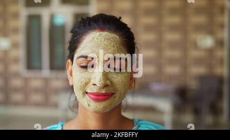 Belle jeune femme utilisant un masque facial maison sur le visage et se détendre à la maison. Femmes asiatiques avec Multani Mitti et Rose Water face Pack. Portrait de sp Banque D'Images