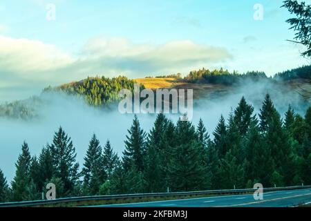 Misty Mountains - vue de l'autoroute de montagne lointaine dans la lumière du soleil au-dessus du brouillard installé dans la vallée des montagnes de la Californie du Nord avec e Banque D'Images