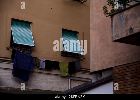 Fenêtres fermées par des rideaux et des vêtements accrochés à la façade d'un condominium Banque D'Images