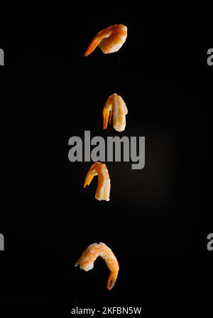 Appétissant crevettes d'orange dans le vol congelé sur fond noir. Produit prêt à l'emploi. Aliments sains, vitamines, protéines. Livre de recettes, blog alimentaire. Banque D'Images