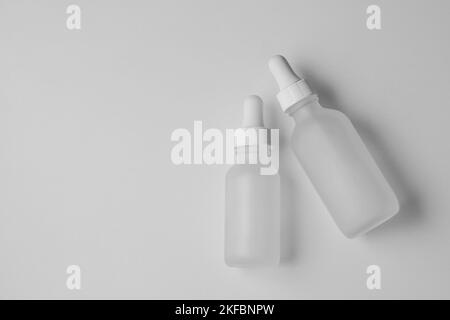 Deux flacons compte-gouttes en verre translucide vides. Mise à plat de flacons de différentes tailles sur fond blanc. Maquette horizontale et espace de copie. Banque D'Images