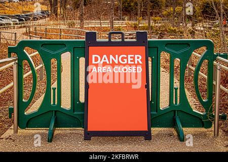 Portail modulaire vert extérieur sur galets publics et trottoir en béton avec affichage sandwich lecture DANGER zone fermée - Bois et parking à distance Banque D'Images