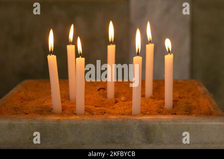 Goias, Brésil – 12 novembre 2022 : plusieurs bougies allumées dans un support de sable de l'église. Bougies allumées dans le temple, feu Saint. Banque D'Images